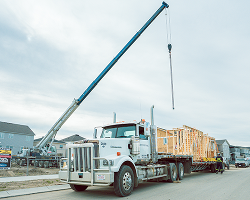 McIntyre Crane mobile crane unloading prefabricated home sections in Calgary residential neighborhood